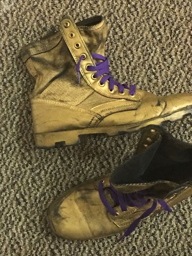 an old pair of shoes with purple laces on them sitting on the floor in front of a carpeted area