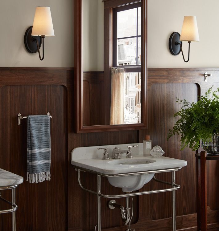 a white sink sitting under a bathroom mirror next to a wall mounted faucet