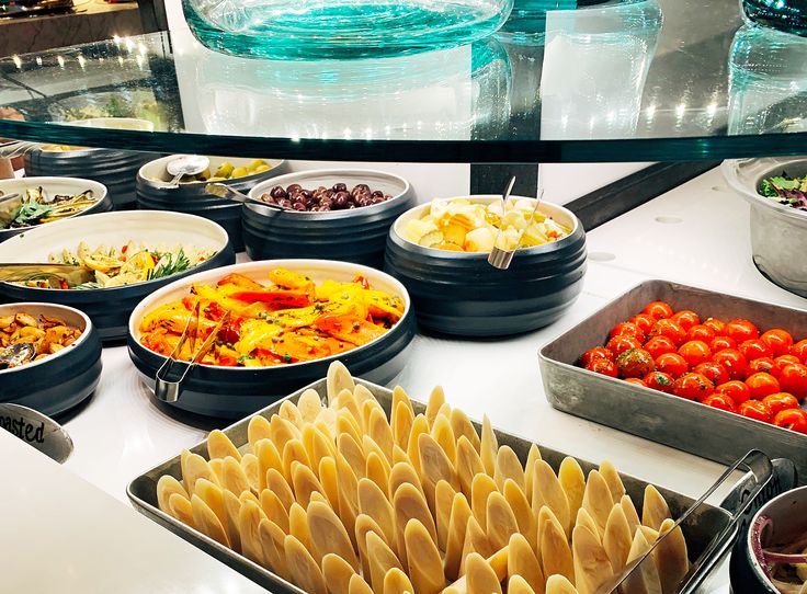 a buffet table filled with lots of different types of food on plates and trays