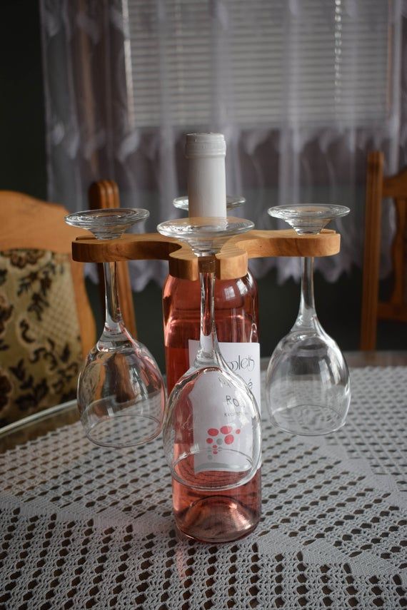 two wine glasses sitting on top of a table next to a bottle and glass holder