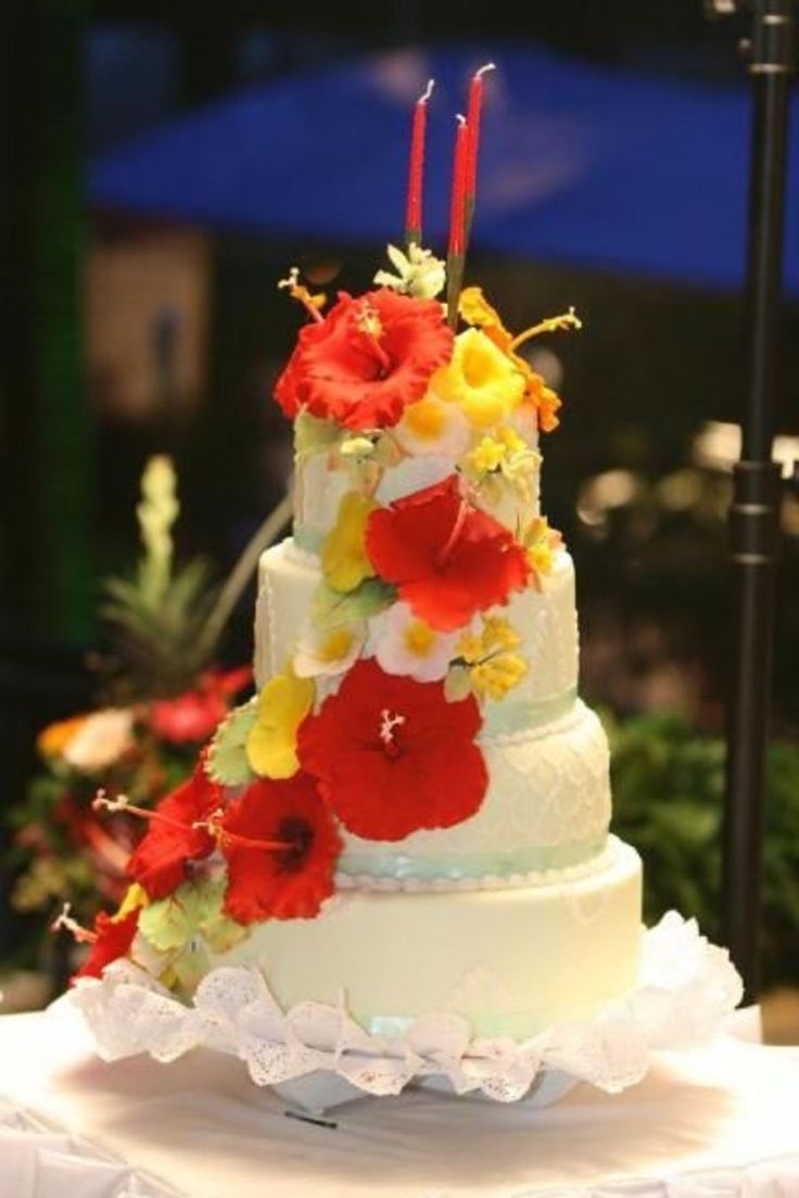 a three tiered cake with flowers and candles on the top is sitting on a table