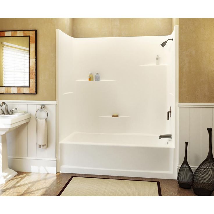 a white bath tub sitting next to a sink in a bathroom with beige walls and wooden floors