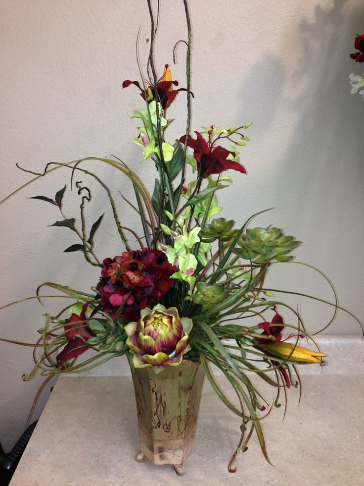 a vase filled with lots of flowers sitting on top of a white tablecloth covered floor