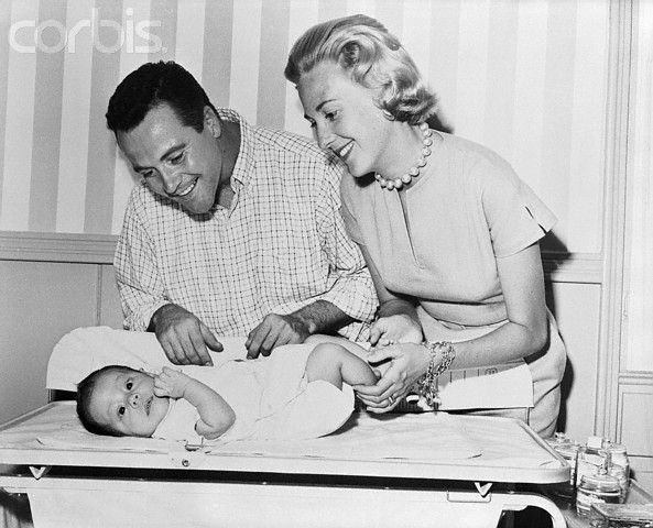 an old photo of a man and woman holding a baby