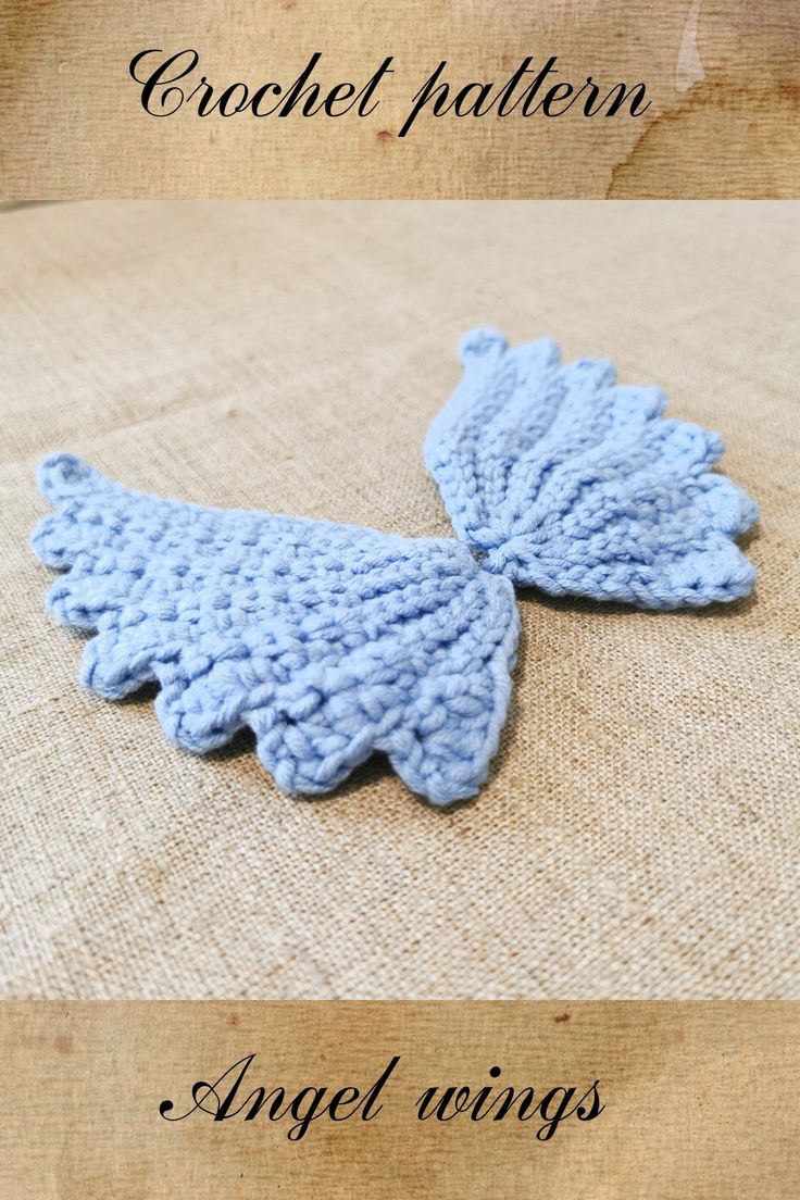 an angel wings brooch is shown in blue yarn and sits on a piece of burlock