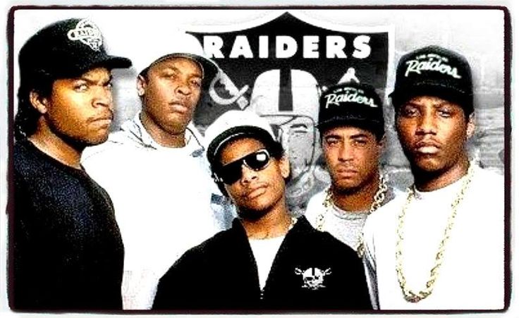 four men standing next to each other in front of a sign that says raiders on it