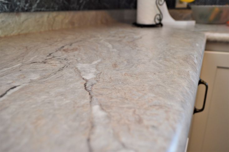 a kitchen counter top that is made out of marble and has a white vase on it