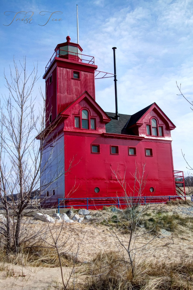 a large red building sitting on top of a sandy beach next to a small tree