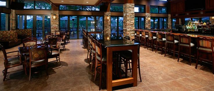 a bar with lots of chairs and tables in a room that has large windows on both sides