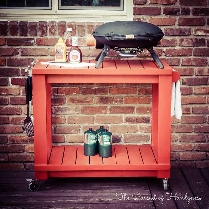 an orange cart with bbq grill and two cans of ketchup