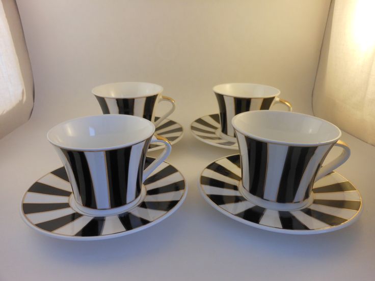 three black and white cups and saucers on a table