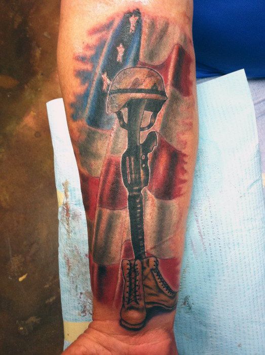 a man with a tattoo on his arm holding a wrench in front of an american flag