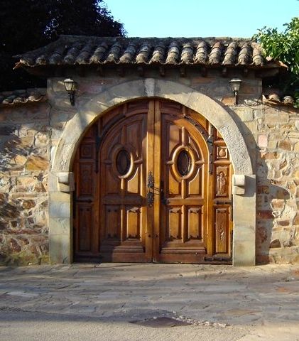 an old stone building with two wooden doors on the front and side entrance to it