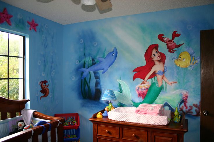 a baby's room with a mermaid theme painted on the wall and crib