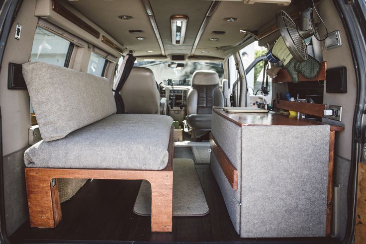 the interior of an rv with two couches and tables in front of it's rear door