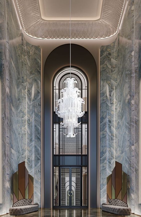 an elegant entry way with two chairs and a chandelier hanging from the ceiling