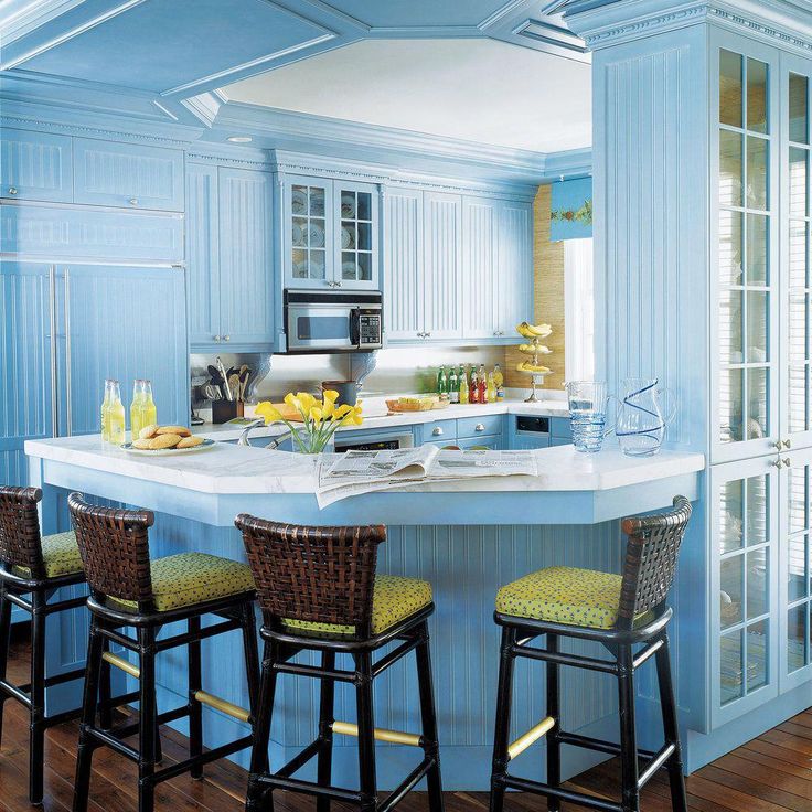 a kitchen with blue walls and white counter tops, four stools in front of the island