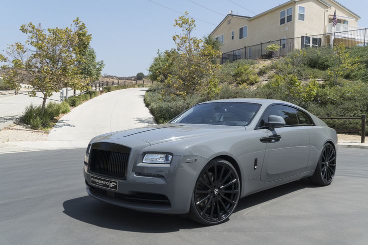 a grey rolls royce parked in front of a house