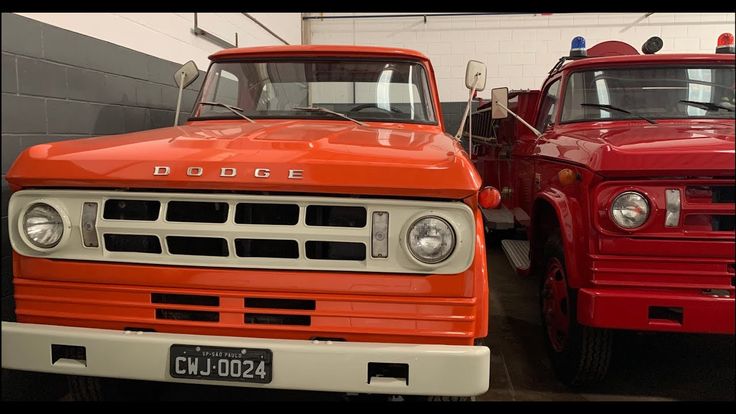 two red trucks parked next to each other in a garage with one truck facing the camera