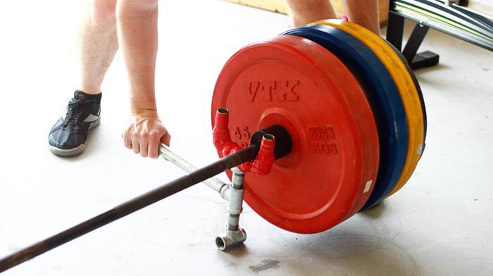 a man holding a barbell in his right hand while standing next to another person