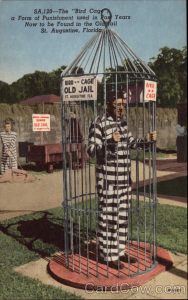 an old jail cell with a man in striped pajamas holding a sign that says,