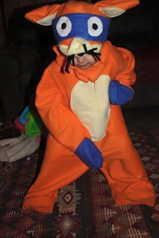 a person in an orange and blue animal costume standing on a rug with their arms around each other