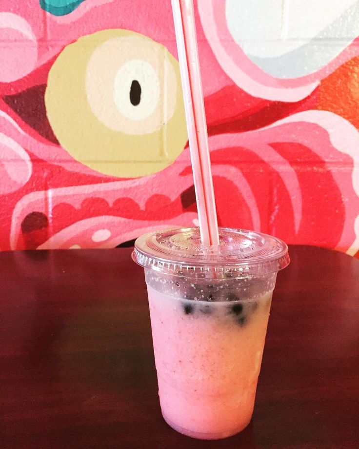 a pink drink sitting on top of a wooden table