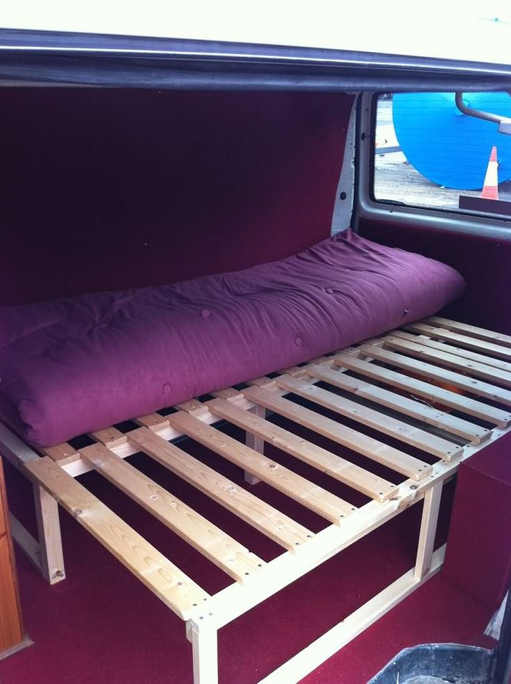 a bed in the back of a van with a purple pillow on it's side