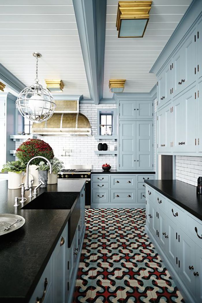 a kitchen with blue cabinets and black counter tops in the center is decorated with red flowers