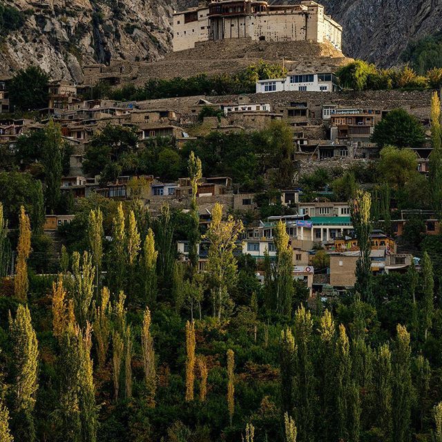 an old building on the side of a mountain with lots of trees in front of it