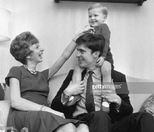 an old black and white photo of a woman holding a young boy on her shoulders