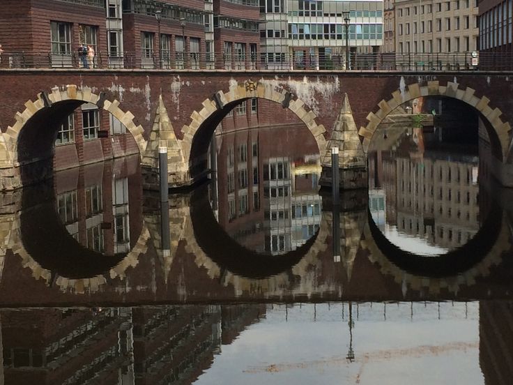 an old brick bridge over a river with buildings in the background