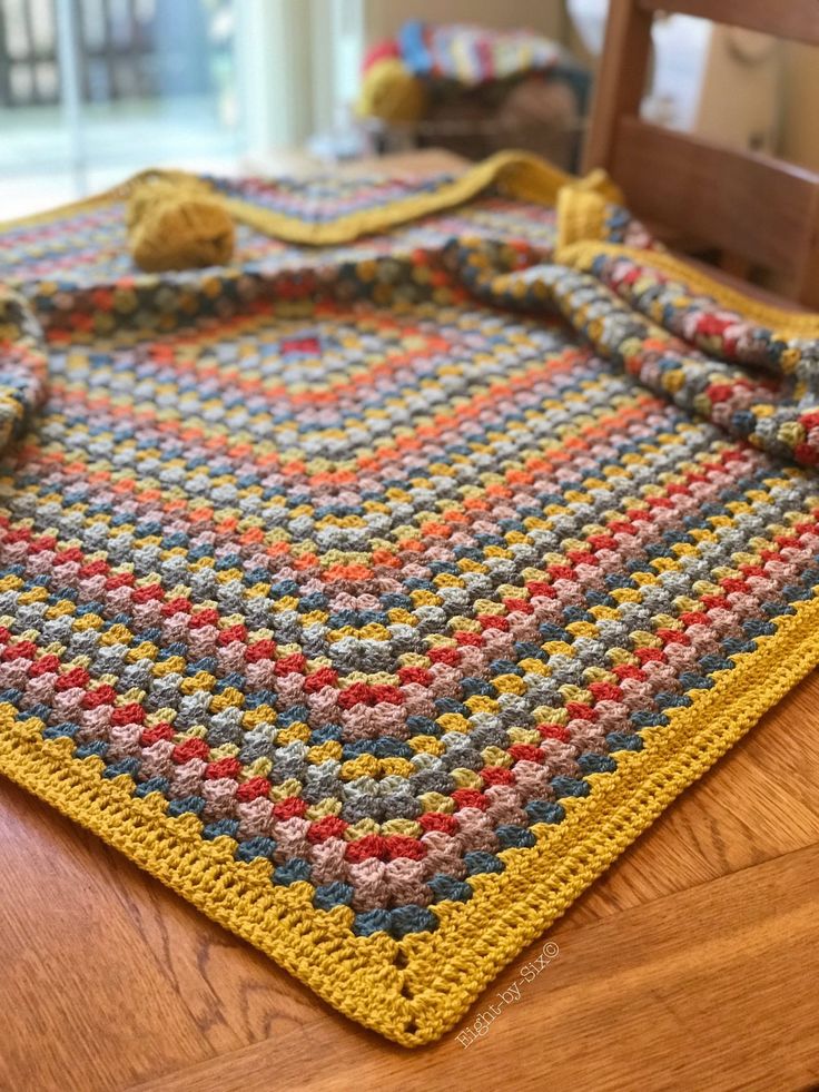 a crocheted table cloth on top of a wooden table next to a chair