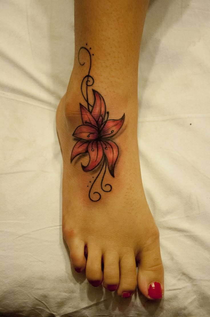 the foot is decorated with flowers and leaves on it's side, along with other tattoos