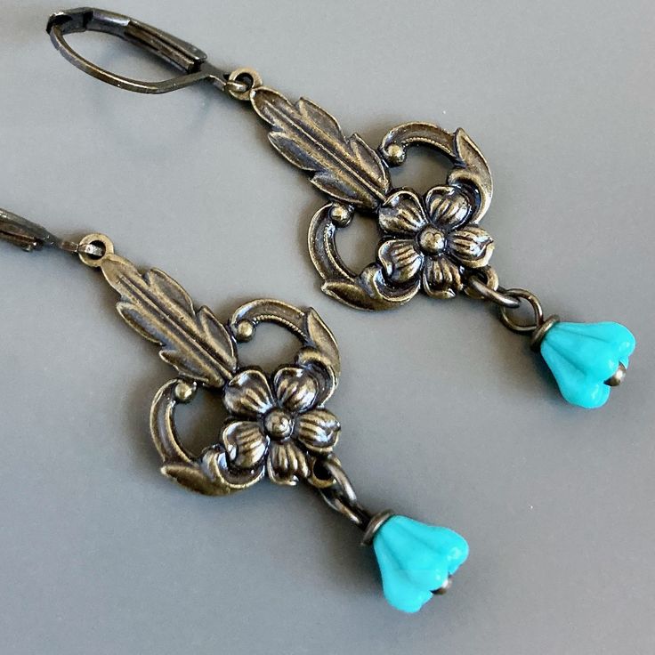 "Turquoise Flower Earrings - Small Turquoise Czech Glass Flowers dangle from Ornate Antiqued Brass Flower stampings that have a lot of detail. The stamping charms have hollow backs and are lightweight. The earrings measure  just over 1.75\" from top of earwires to bottom  Antiqued Brass Leverback Earwires" Vintage Turquoise Flower Earrings, Vintage Turquoise Dangle Flower Earrings, Turquoise Flower Charm Dangle Jewelry, Turquoise Dangle Jewelry With Flower Charm, Vintage Drop Earrings With Flower Charm, Turquoise Dangle Earrings With Flower Charm, Nickel Free Turquoise Flower Earrings, Turquoise Nickel Free Flower Earrings, Elegant Turquoise Earrings With Flower Charm