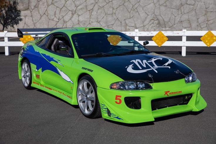 a green sports car with graffiti painted on it's hood parked in a parking lot