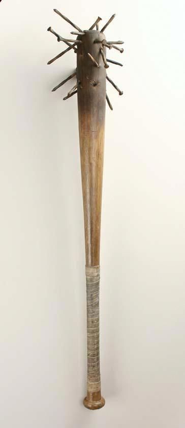 a baseball bat that is leaning against the wall with spikes on it's head