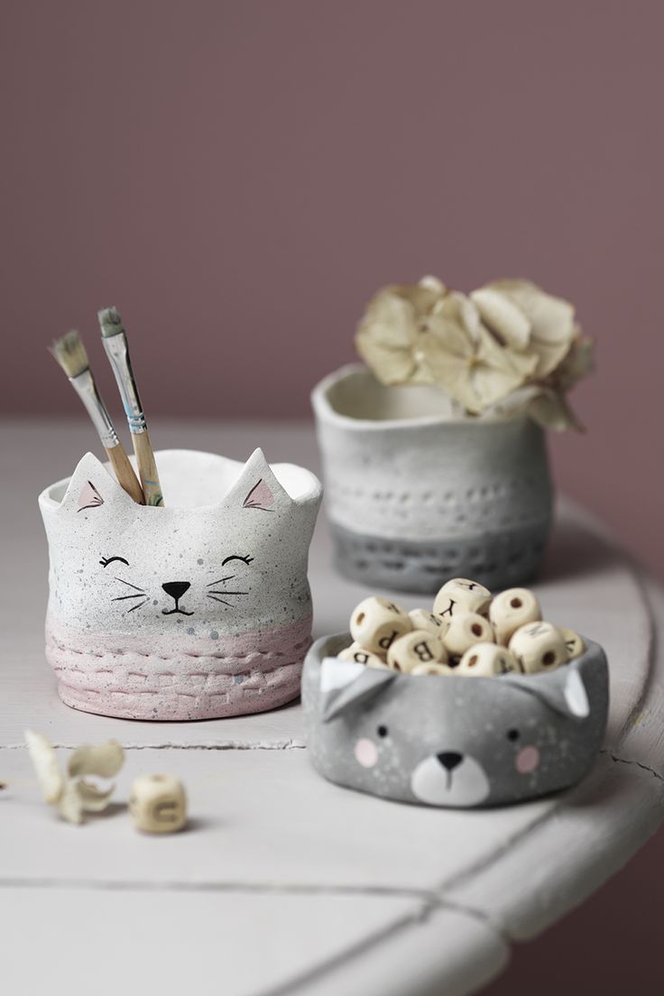 two ceramic bowls with cat faces and flowers in them on a white countertop next to each other