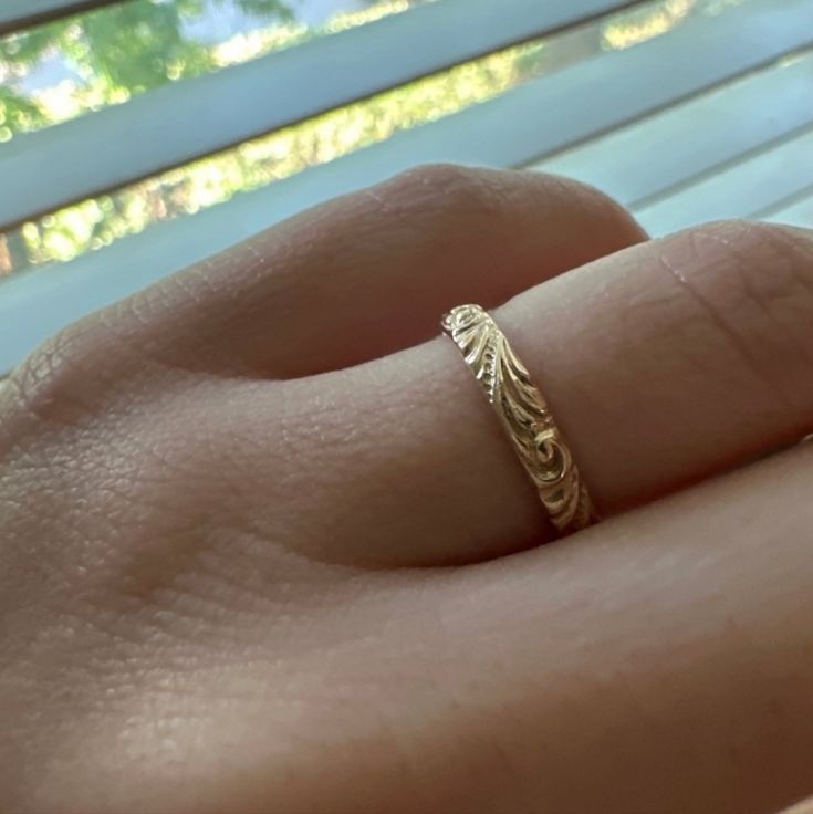 a close up of a person's hand with a gold ring on their finger