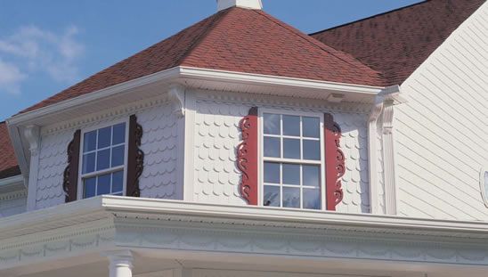 a large white house with red shutters and a clock on the top of it