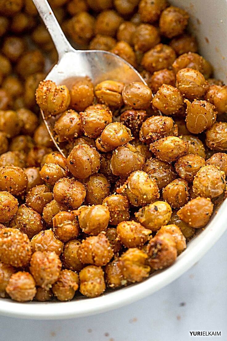 a white bowl filled with cooked chickpeas and a spoon in the bowl next to it