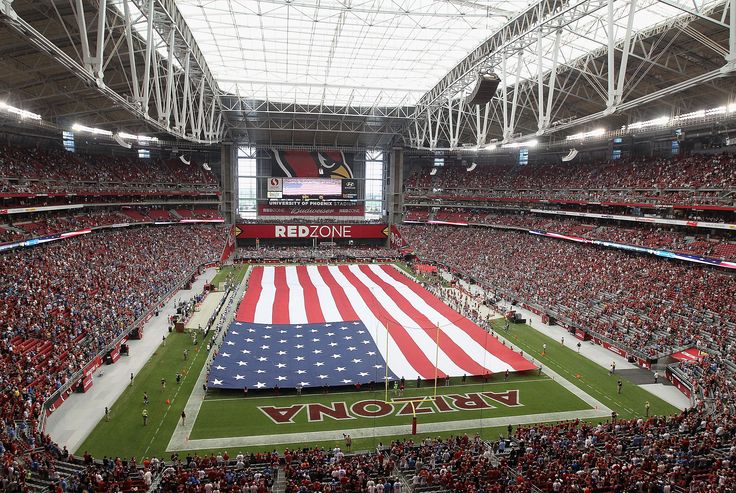 a large american flag is on the field in front of an audience at a football game