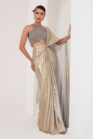 Grey and gold toned pre-draped saree crafted in metallic georgette. Paired with a sleeveless halter neck blouse with tonal crystal tassel and cutdana embellishments. - Aza Fashions Gold Pre-draped Saree For Party, Gold Pre-draped Saree For Reception And Festive Occasions, Gold Pre-draped Saree With Zari Work, Pre-draped Saree With Zari Work For Festive Occasions, Gold Pre-draped Saree For Diwali Reception, Glamorous Silk Draped Saree, Fitted Gold Pre-draped Saree For Festive Occasions, Pre-draped Blouse Piece With Zari Work For Reception, Gold Pre-draped Saree For Diwali Evening