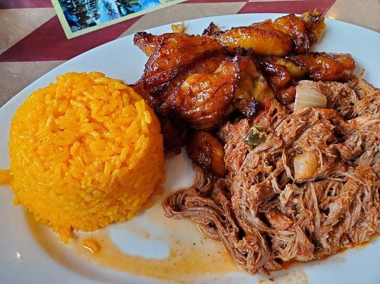 a white plate topped with meat, rice and other food on top of a table