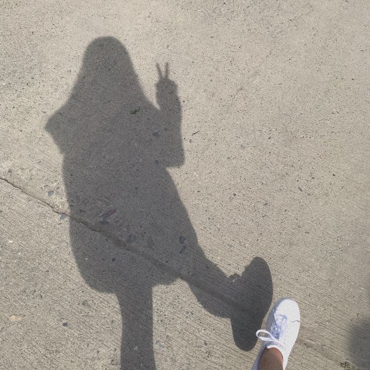 the shadow of a person standing in front of a skateboard with his hand up