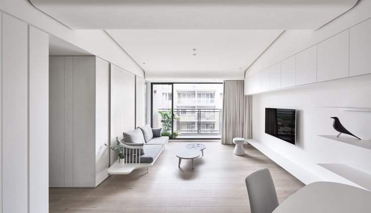 an empty living room with white furniture and wood flooring is seen in this image