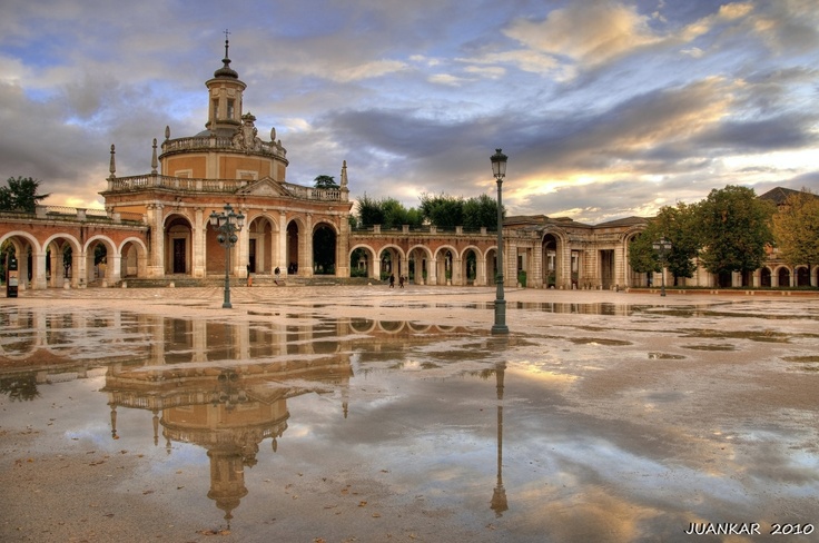 a large building with a clock tower and water puddles in the middle of it