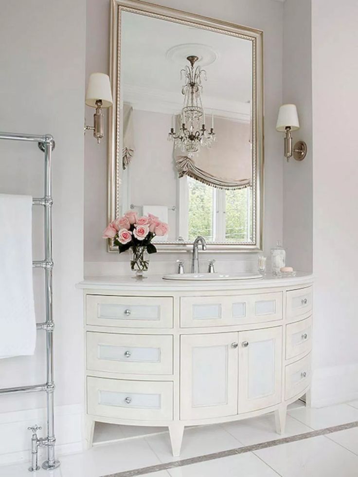 a white bathroom with a chandelier and mirror