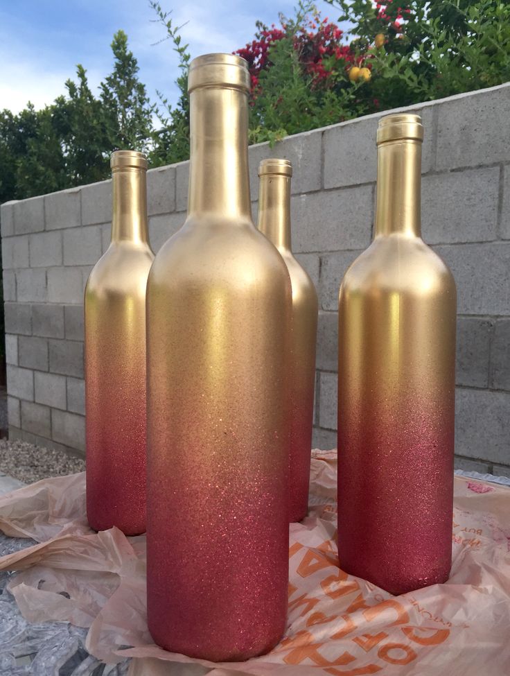 three wine bottles sitting on top of a sheet of plastic next to a brick wall