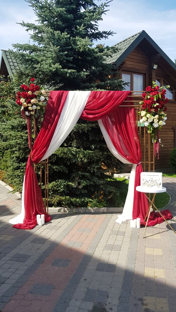 a red and white wedding arch decorated with flowers